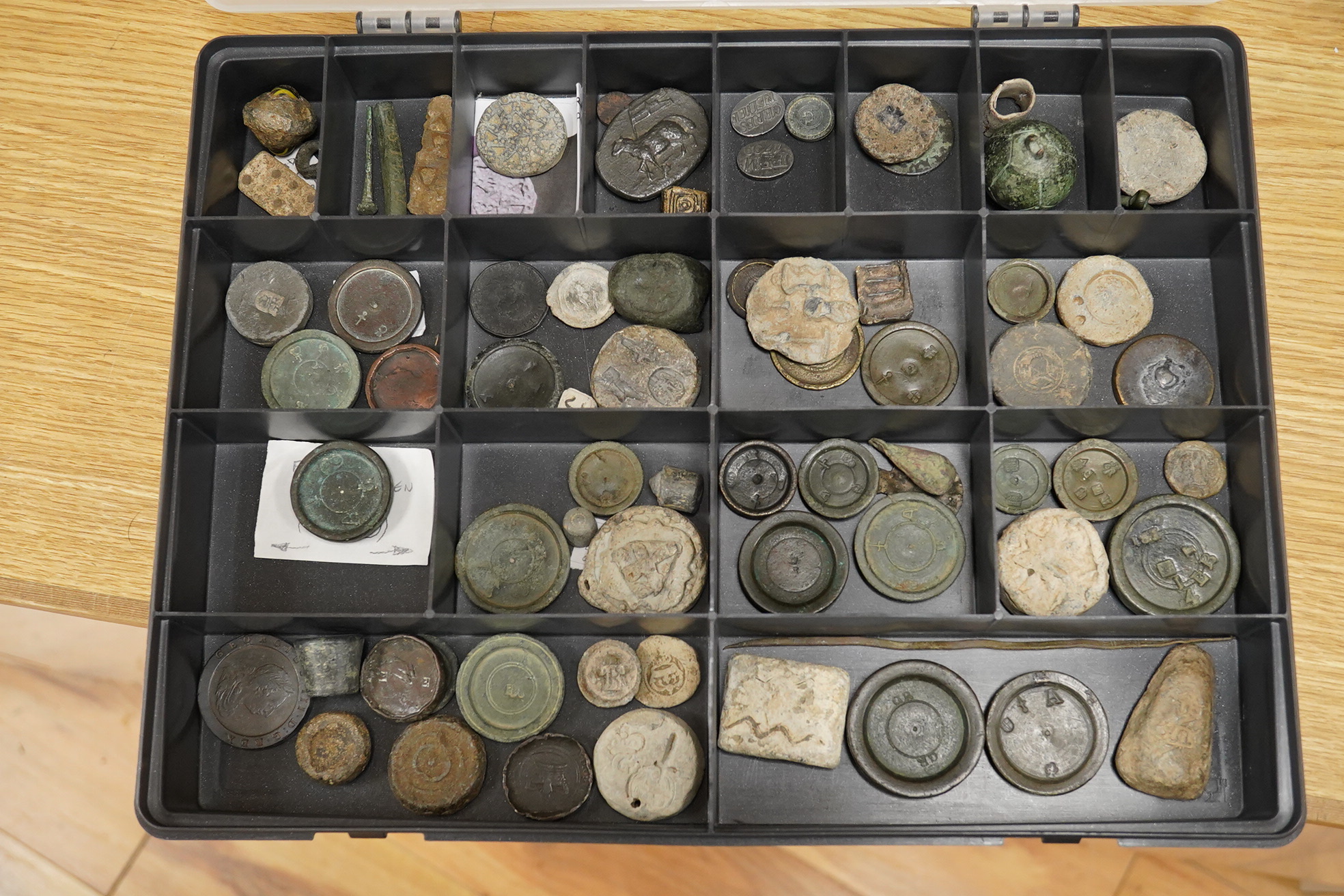 A collection of 16th century to 19th century bronze and lead circular trade weights, stamped with Royal Cyphers, weights, proof marks, the assay dagger for London, etc., contained within four plastic collector’s trays